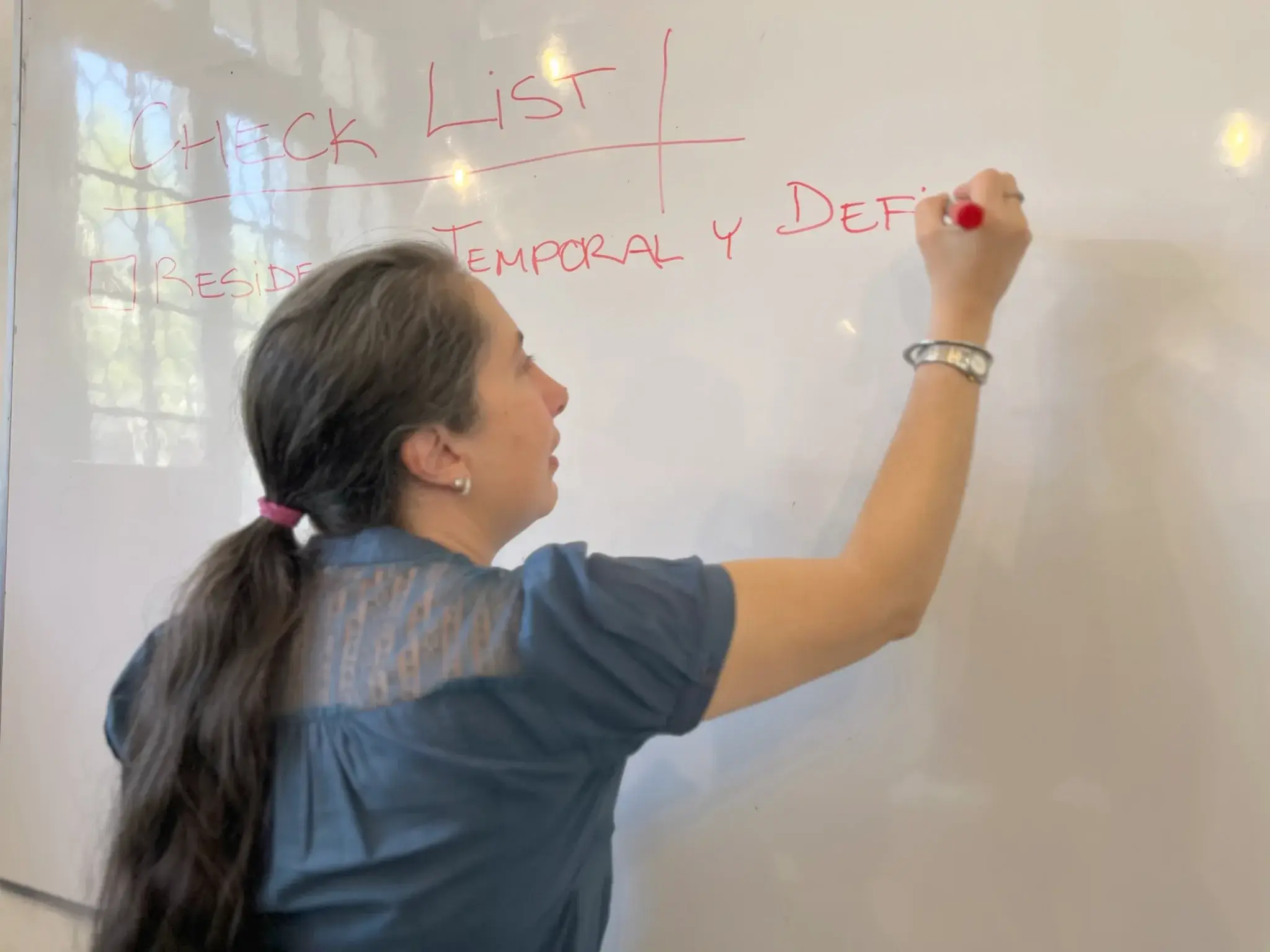 Una integrante del equipo de Seraf escribiendo un check list de residencia temporal y definitiva en una pizarra